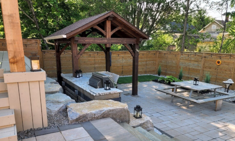 Backyard fitted with outdoor kitchen and gazebo on concrete patio stones